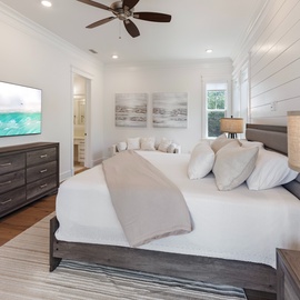You'll love unwinding in this coastal-chic bedroom, where crisp white shiplap walls and soothing ocean artwork set the scene for your perfect beach escape. Sink into plush bedding after a day exploring.