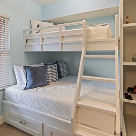 Your kids will love this cozy bunk bed room with built-in storage shelves and soft blue walls creating the perfect sleepover atmosphere.