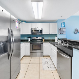 Your fully equipped kitchen features modern stainless steel appliances, granite countertops, and peaceful blue walls perfect for home cooking.