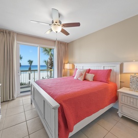 Wake up to stunning ocean views from your cozy bedroom, where vibrant coral bedding and soft lighting create the perfect coastal retreat.