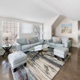 Relax in your bright, modern living room with comfortable seating, natural light, and elegant hardwood floors.