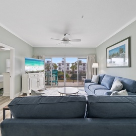 Unwind in your spacious living room with soft blue tones and tropical touches, where ocean views greet you through the balcony doors.