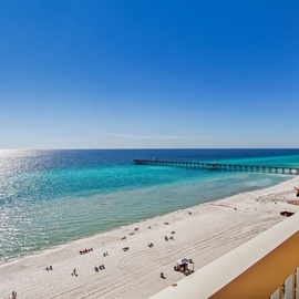 Stunning beachfront view showcases pristine white sand, turquoise waters, and a scenic pier stretching into the Gulf of Mexico.