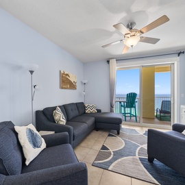 Unwind in your spacious living room with comfortable seating, a gentle ceiling fan, and stunning ocean views through sliding doors to your private balcony.