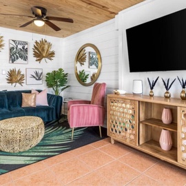 Sink into this vibrant living room where teal velvet meets tropical charm—your perfect retreat with modern comfort and coastal flair.