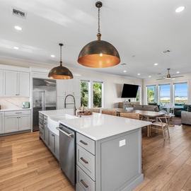 You'll love cooking in this spacious gourmet kitchen with sleek countertops, modern appliances, and warm pendant lighting overlooking your ocean-view living space.