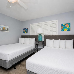 The guest bedroom features two comfortable beds, vibrant artwork, and a charming nightstand with a decorative lamp