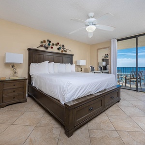 Bright master bedroom featuring a king bed, stylish decor, and sliding glass doors leading to the beachfront balcony