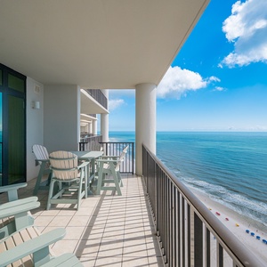 Relax on the spacious balcony with coastal views, featuring comfortable seating and a perfect spot for morning coffee