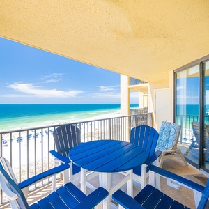 Enjoy a relaxing outdoor dining experience on the balcony with a stunning view of the beach and clear blue skies