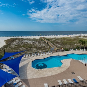 Relax by the pool, surrounded by vibrant blue canopies and a view of the beach just steps away