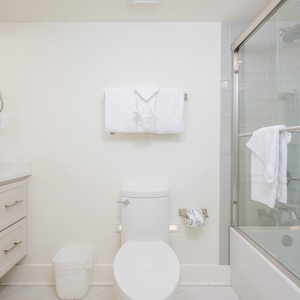 Bright guest bath featuring a tub/shower combo, plush towels, and a sleek vanity, creating a refreshing and inviting vibe