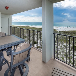 Balcony features a dining table with seating, offering a serene view of the beach and gentle waves of the gulf