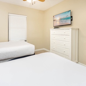 Enjoy restful nights in this guest bedroom featuring two twin beds, a TV, and cheerful decor for a relaxing stay