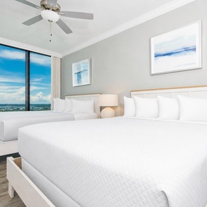 Inviting guest bedroom featuring two comfortable queen beds, a stylish lamp, and breathtaking coastal views