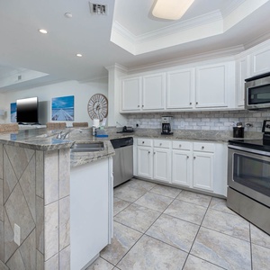 This stylish kitchen features stainless and granite with a sleek backsplash and a view of the beach with an elegant touch
