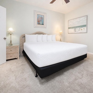 Unwind in the king suite featuring a plush bed, soft lighting, and beach decor for a restful retreat