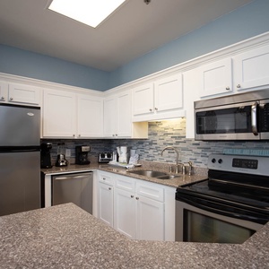 White cabinetry and a granite countertop complement the modern kitchen, featuring a stylish backsplash and ample prep space