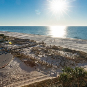 Breathtaking beachfront view featuring glistening water and white sand, with a glimpse of the pool area and surroundings