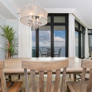 Bright dining area with a wooden table, stylish chandelier, and breathtaking views through floor-to-ceiling windows