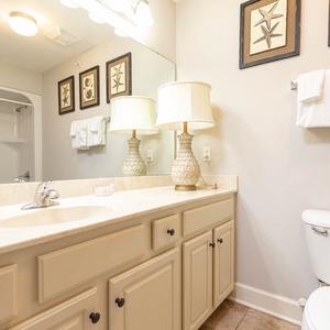 The guest bathroom features a light-colored vanity, decorative starfish art, and a cozy ambiance with a lamp and fresh towels