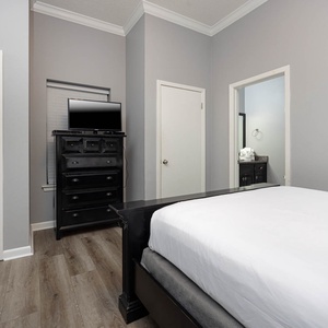 Comfortable guest bedroom featuring a queen bed and a twin bed, a TV, and adjoining bathroom