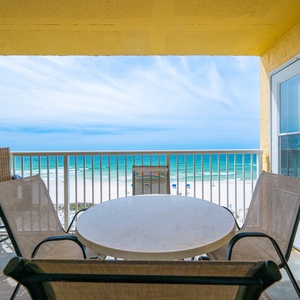 Enjoy stunning beachfront views from this cozy balcony, featuring a round table and comfortable seating for relaxation