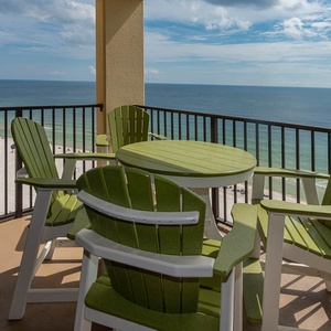 Relax in the green Adirondack chairs with a round table, offering a scenic view of the beach and calm waters