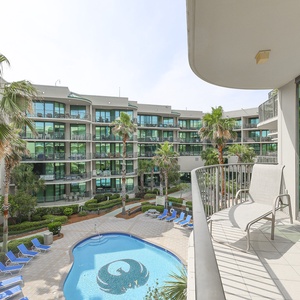Enjoy gentle breezes while soaking in the vibrant sights of the lush pool area from your spacious balcony