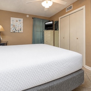 The bedroom features a king bed, a cozy lamp, and a TV, complemented by soft curtains and artwork