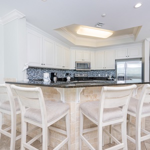Modern kitchen with granite countertops, stainless appliances, and comfortable bar seating for casual dining