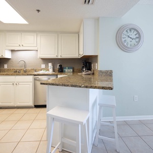 Kitchen featuring white cabinetry, granite countertops, coffee station, and a breakfast bar with stools
