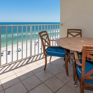 Enjoy a beachfront view from this cozy dining area featuring a round table and stylish blue cushioned chairs
