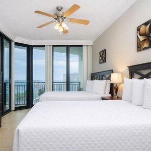 Bright and inviting guest bedroom featuring two full beds, a flat-screen TV, and stunning views from large windows