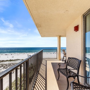 Enjoy a relaxing moment on the balcony with views of the beach and gentle waves, featuring stylish seating for comfort