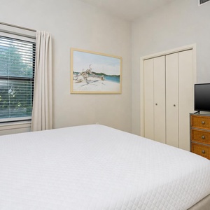 Relax in this comfortable guest bedroom featuring a queen bed, a TV, and artwork that enhances the vibe