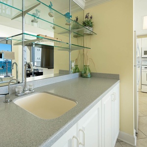 Stylish kitchen area wet bar features a spacious countertop and galssware display with coastal decor