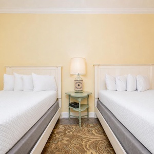 Inviting guest bedroom featuring two queen beds and a charming side table with a decorative lamp