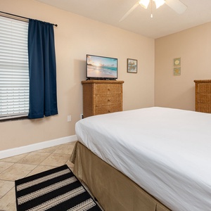 Guest bedroom featuring a comfortable queen bed, stylish wicker dressers, and a flat-screen TV for relaxing evenings