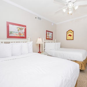 Brightly decorated guest room featuring two double beds, whimsical beach-themed art, and a cozy ambiance for relaxation