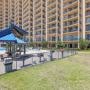 Picnic and pool area with a blue roof overlooks the pool, surrounded by lounge chairs and the Phoenix V amenities