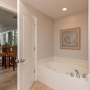 This bathroom features a relaxing jetted tub and a serene view of the living area with stylish bar seating