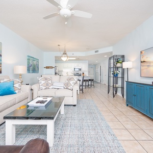 Light and airy living area features a comfortable sofa with queen sleeper, vibrant accents, and a large TV