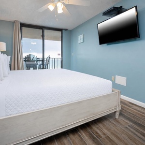 Relax in this tranquil master bedroom featuring a comfortable king bed, a large TV, and beachfront balcony access