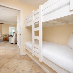 This cozy nook features a white bunk bed, perfect for kids, with a view of the inviting living area and dining space