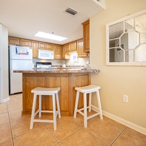Wooden cabinetry complements the modern breakfast bar and breakfast bar with seating, creating a welcoming space