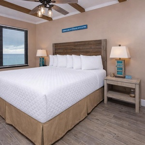 Master bedroom featuring a plush king bed and inviting views through large windows, perfect for a relaxing getaway