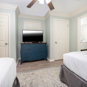 Brightly colored walls frame a cozy guest room featuring two double beds, a TV on a blue dresser, and en-suite bathroom