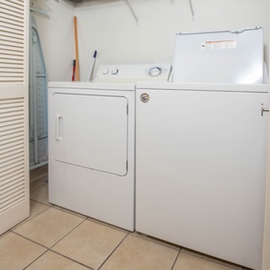 The laundry area features a washer and dryer alongside an ironing board, offering convenience for guests during their stay