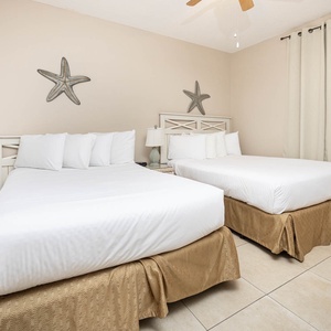 Rest comfortably in this guest bedroom with two double beds, soft linens, and charming coastal decor for a relaxing stay
